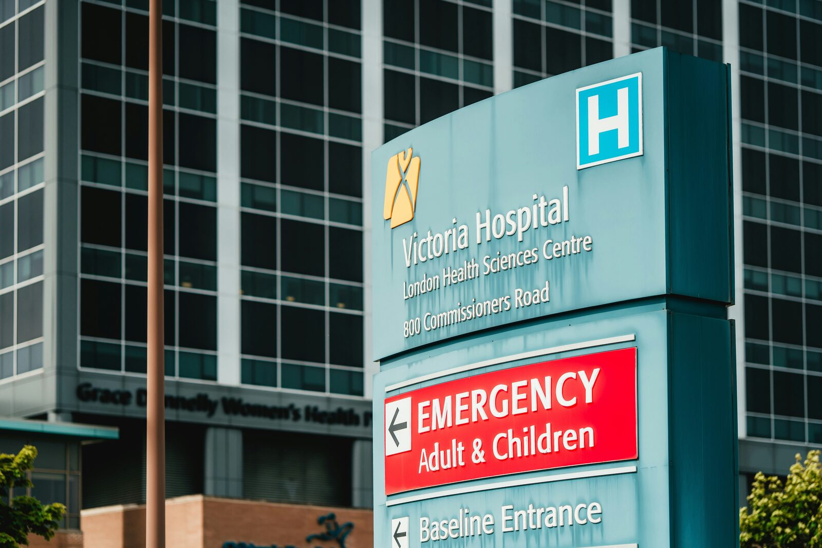 Victoria Hospital sign with Emergency entrance and modern building in background.