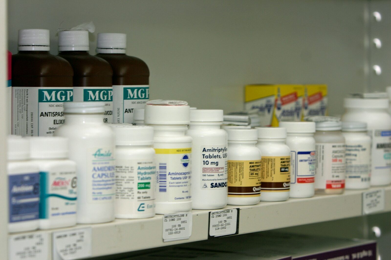 A pharmacy shelf stocked with medicines in bottles and boxes